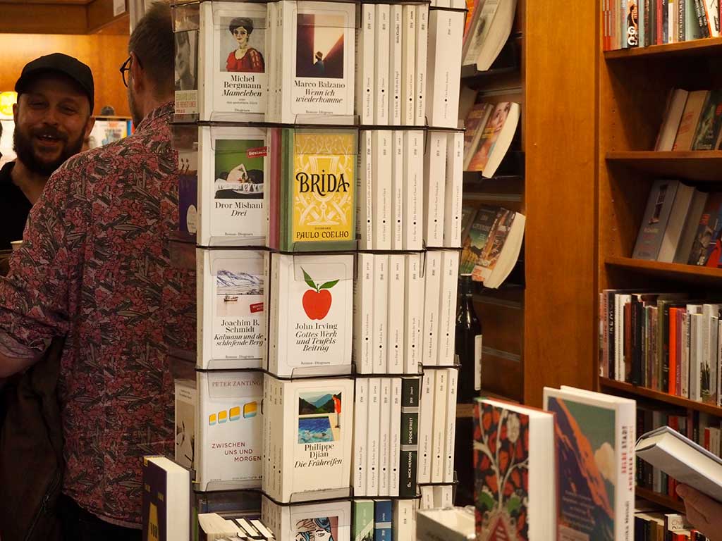 View into the shop: stacks of books and shelves, in the foreground two visitors